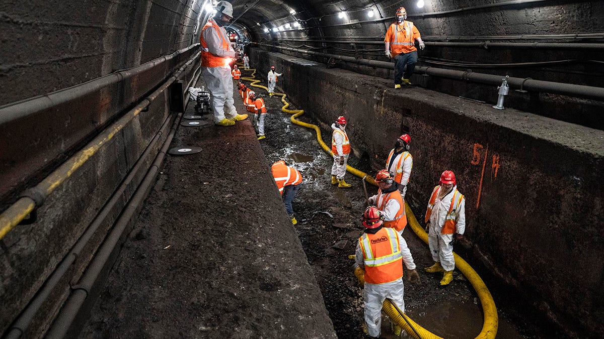 FILE - In this March 20, 2021 file photo, Amtrak workers perform tunnel repairs to a partially flooded train track bed, in Weehawken, N.J. (AP Photo/John Minchillo, File)