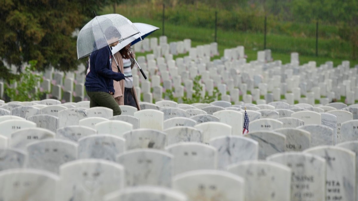 Woman carries umbrella while in cemetery on Memorial Day