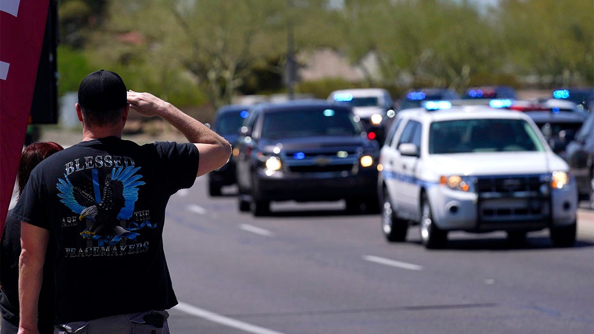 People line the streets as the body of Chandler Police Officer Christopher Farrar, killed in the line of duty last Thursday, is escorted during a large multi-jurisdiction police procession Friday, May 7, 2021, in Chandler, Ariz. Officer Farrar was struck by a suspect in a stolen vehicle after a long police chase. (AP Photo/Ross D. Franklin)