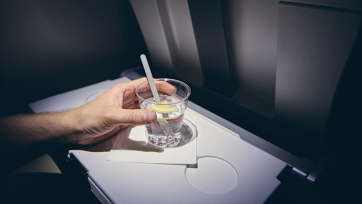 person drinking alcohol on plane