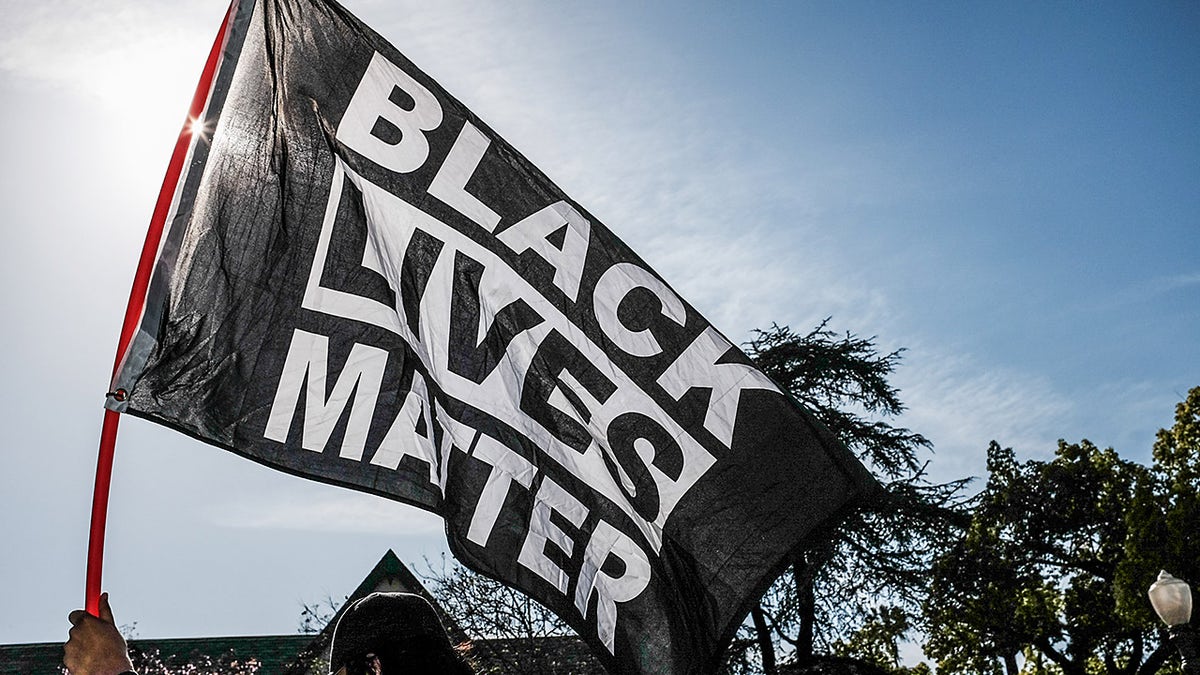 LOS ANGELES, CALIFORNIA, UNITED STATES - 2021/04/20: A protester waves a Black Lives Matter flag during the demonstration. Hours after the verdict of the Derek Chauvin trial, protesters meet outside of Los Angeles Mayor Eric Garcetti's home to protest his proposed funding of the Los Angeles Police Department. 
