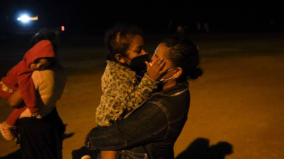 A migrant child from Honduras kisses her mother through masks at an intake area after they turned themselves in upon crossing the U.S.-Mexico border, late Tuesday, May 11, 2021, in La Joya, Texas. The U.S. government continues to report large numbers of migrants crossing the U.S.-Mexico border with an increase in adult crossers. But families and unaccompanied children are still arriving in dramatic numbers despite the weather changing in the Rio Grande Valley registering hotter days and nights. (AP Photo/Gregory Bull)