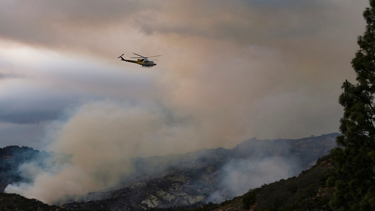 A helicopter flies over a brush fire scorching the Pacific Palisades area of Los Angeles on Sunday. (AP)