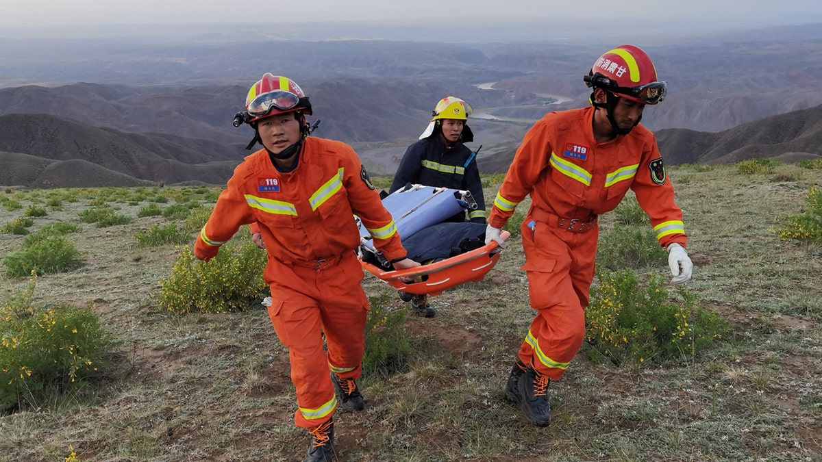 Rescuers carrying equipment as they search for runners who were competing in a 100-kilometre cross-country mountain race when extreme weather hit the area, leaving at least 20 dead, near the city of Baiyin in China's northwestern Gansu province.