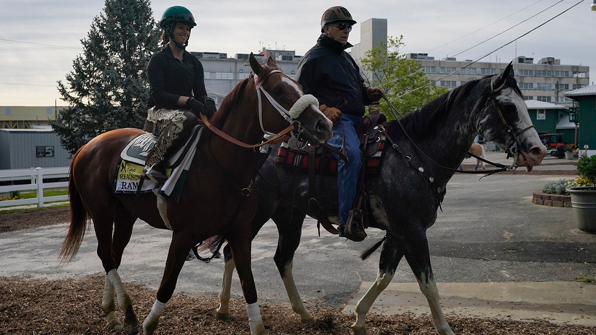 Exercise rider Jade Cunningham, left, walks with Preakness entrant Ram and trainer D. Wayne Lukas after a training session ahead of the Preakness Stakes horse race at Pimlico Race Course, Wednesday, May 12, 2021, in Baltimore. (AP Photo/Julio Cortez)