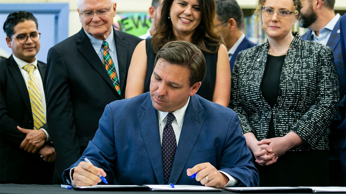 Florida Gov. Ron DeSantis, center, signs bills revamping Florida's literacy and early childhood learning in West Miami Middle School in Miami on Tuesday, May 4, 2021.