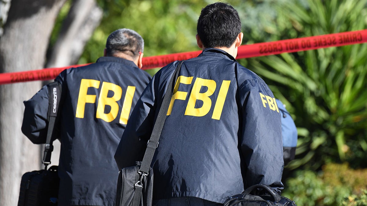 Agents from the Federal Bureau of Investigation walk through the crime scene