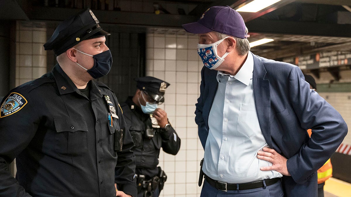 New York City Mayor Bill de Blasio speaks with police officers on the platform of the subway F line
