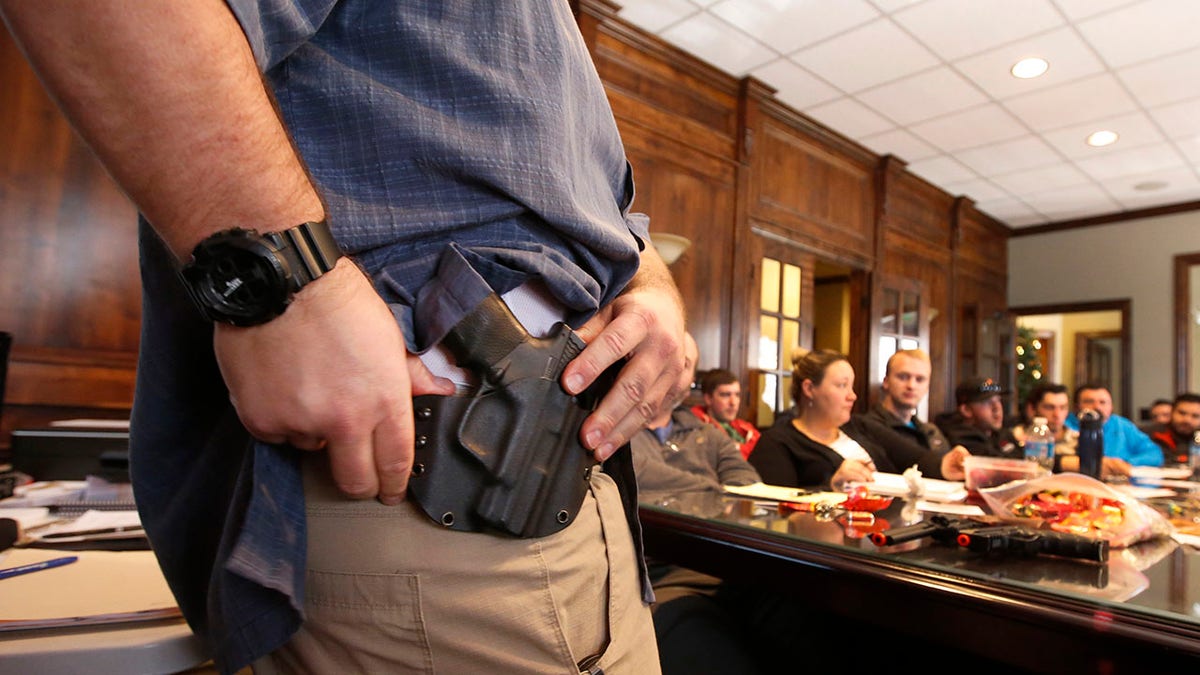 Man displays hip holster with gun at concealed carry weapons class