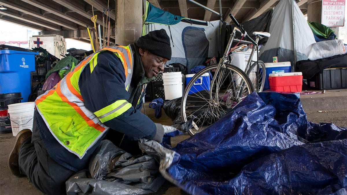 XL Jefferson Jr., 58, rolls up an extra tarp after repairing another person experiencing homelessness' tent on Feb. 13 in Austin, Texas. (Reuters/USA Today Network)