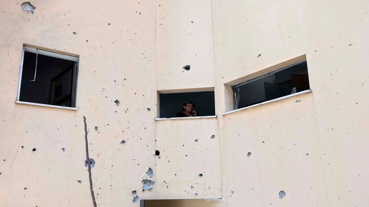 An Israeli woman looks out a window of her house at the site of a rocket attack in the central Israeli city of Petah Tikvah on Thursday. (AP)