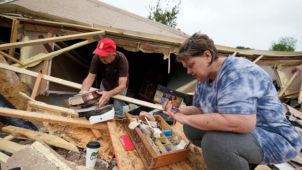 Vickie Savell, right, looks for her wedding band, as a friend and fellow church member pulls possessions from the remains of her new mobile home early Monday, May 3, 2021, in Yazoo County, Miss. Multiple tornadoes were reported across Mississippi on Sunday, causing some damage but no immediate word of injuries. (AP Photo/Rogelio V. Solis)