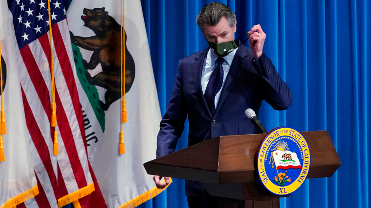 California Gov. Gavin Newsom removes his face mask during a news conference in Sacramento, Calif. 