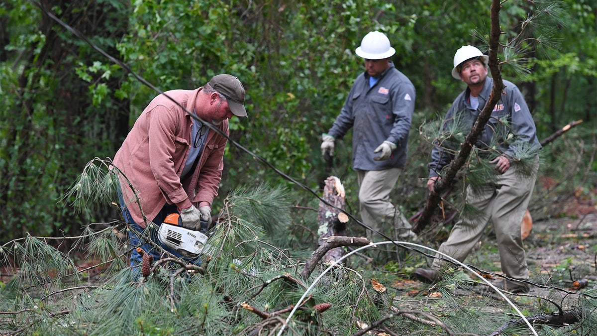 A Tupelo Water and Light crew works to clear downed trees and power lines along Oakview Drive in Tupelo, Miss., Monday, May 3, 2021. (AP Photo/Thomas Graning)