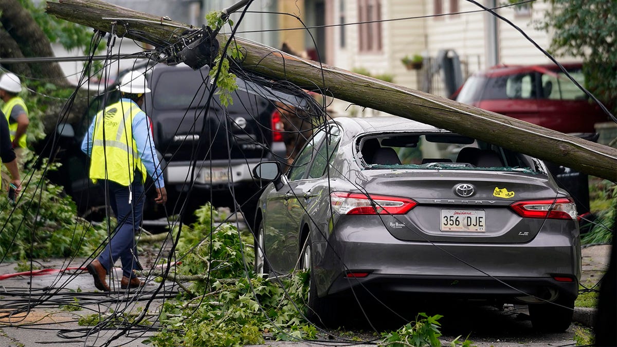 A downed power pole from a possible tornado sits on a damaged car after heavy storms moved through the area Tuesday night, in the Uptown section of New Orleans, Wednesday, May 12, 2021. (AP Photo/Gerald Herbert)