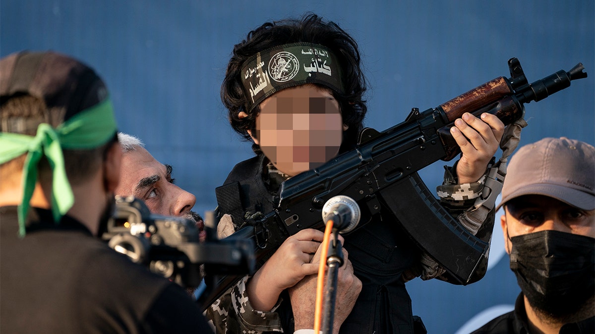 Yahya Sinwar, Palestinian leader of Hamas in the Gaza Strip, second left, holds a child in a soldier costume, on stage with a weapon for the cameras, at a rally of supporters days after a cease-fire was reached in an 11-day war between Gaza's Hamas rulers and Israel, Monday. (AP Photo/John Minchillo)