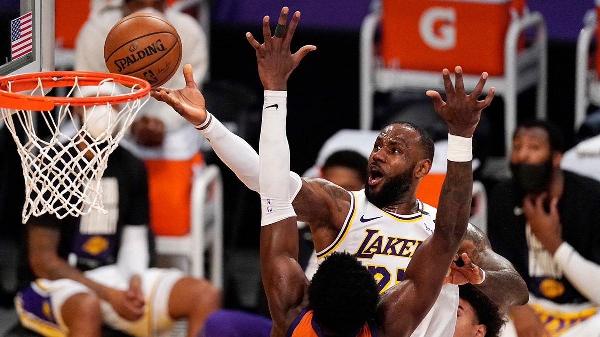 Los Angeles Lakers forward LeBron James, top, shoots as Phoenix Suns center Deandre Ayton defends during the second half in Game 4 of an NBA basketball first-round playoff series Sunday, May 30, 2021, in Los Angeles. (AP Photo/Mark J. Terrill)