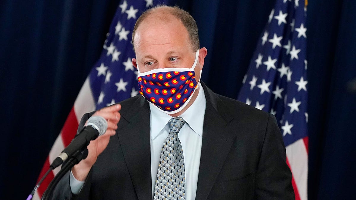 Colorado Gov. Jared Polis wears a face covering as he approaches the podium to make a point about the availability of COVID-19 vaccinations in the state during a news conference on the state's efforts against the coronavirus Tuesday, April 27, 2021, in Denver. (AP Photo/David Zalubowski)
