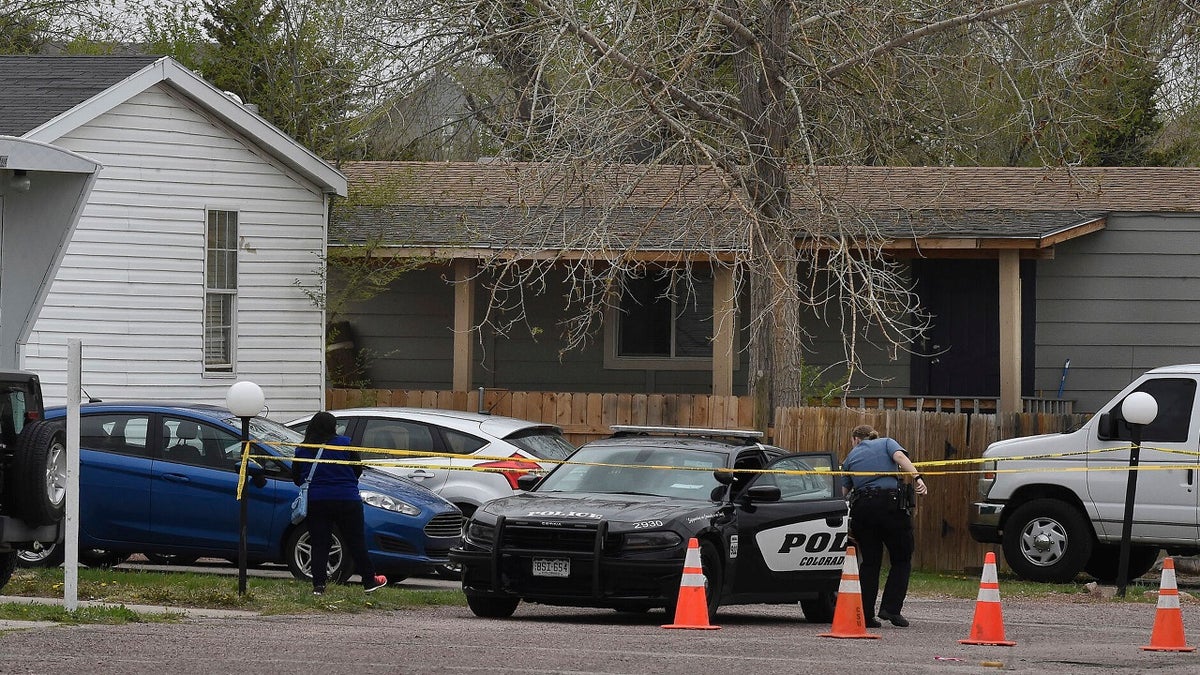 A Colorado Springs police officer goes to help a person who was in a different mobile home get to her car from behind the crime tape in Colorado Springs, Colo., on Sunday. A gunman opened fire at a birthday party in Colorado, slaying six adults before killing himself, police say. (AP/The Colorado Springs Gazette)