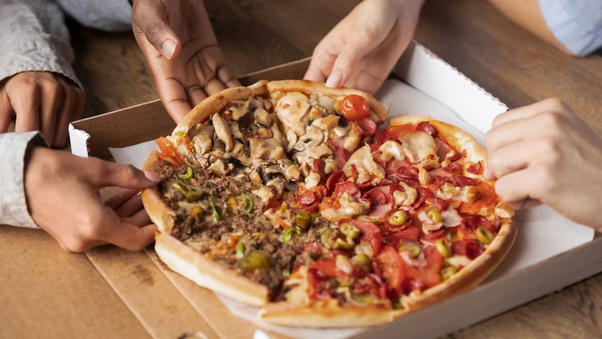 People grabbing slices of different pizza