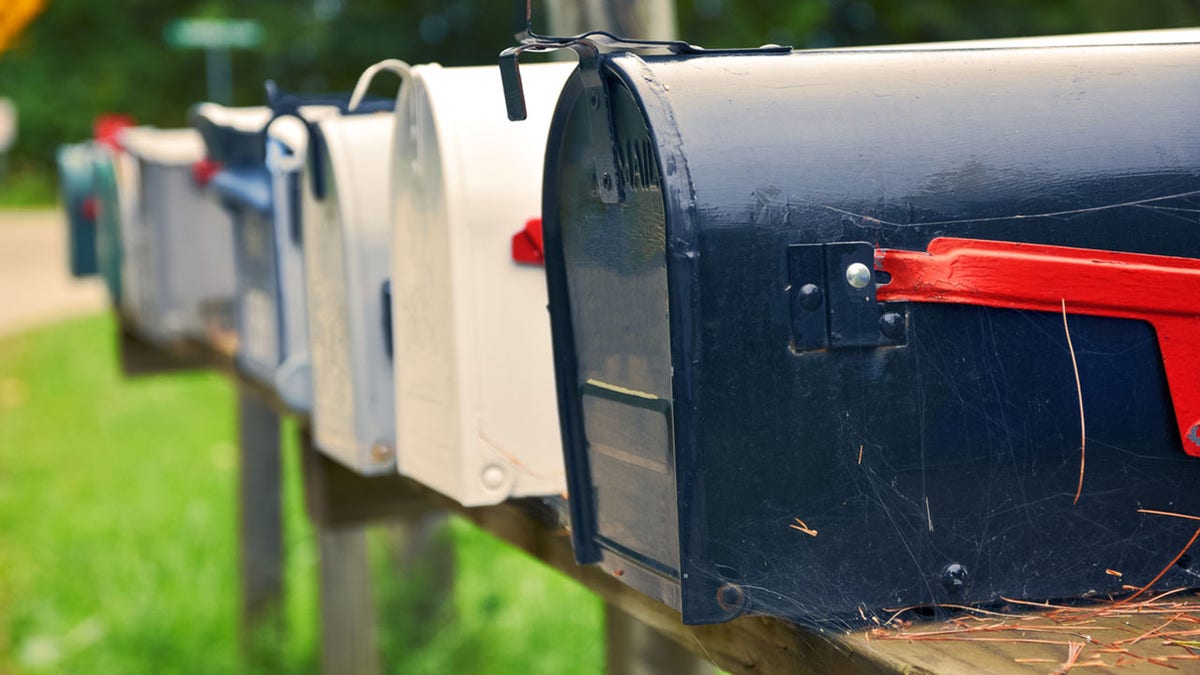 An isolated row of metal US mail boxes on wooden post in the countryside. Spider webs in one of them. Mail concept. New York City. United States