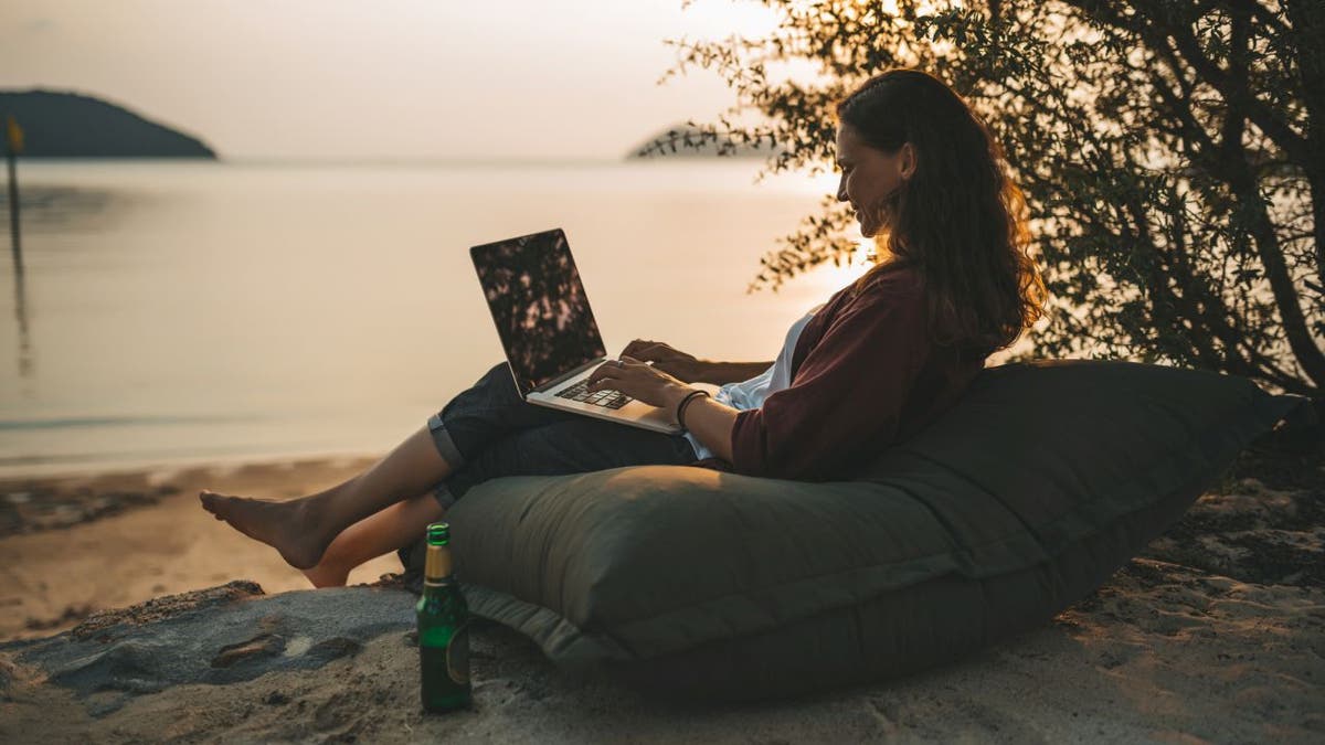 woman on beach with laptop