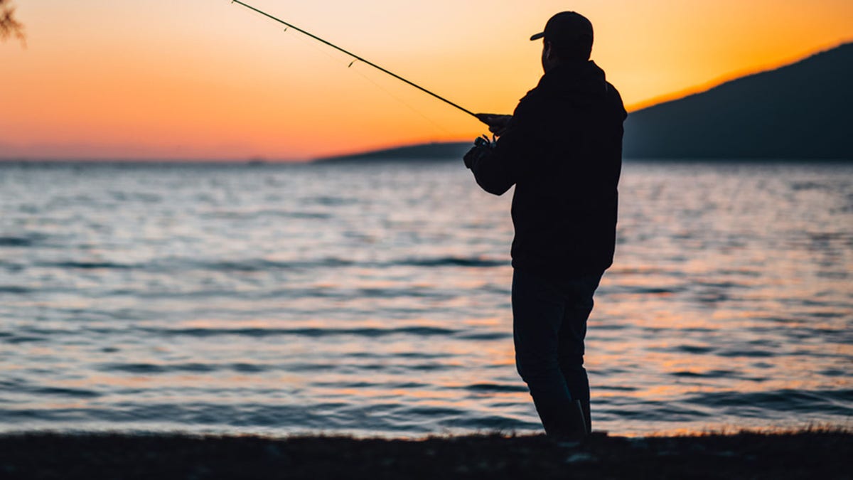 Young Man Fishing at the Beach at Sunset