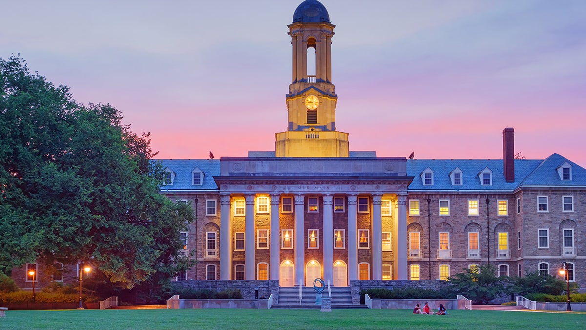 Students chat in front of Old Main, the main administrative building at Penn State University after sunset at University Park in State College, Pa.