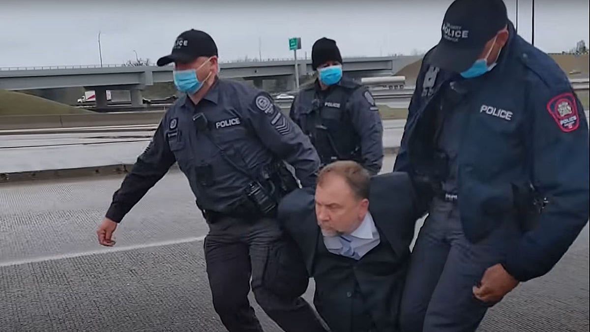 Artur Pawlowski being arrested in a Calgary highway