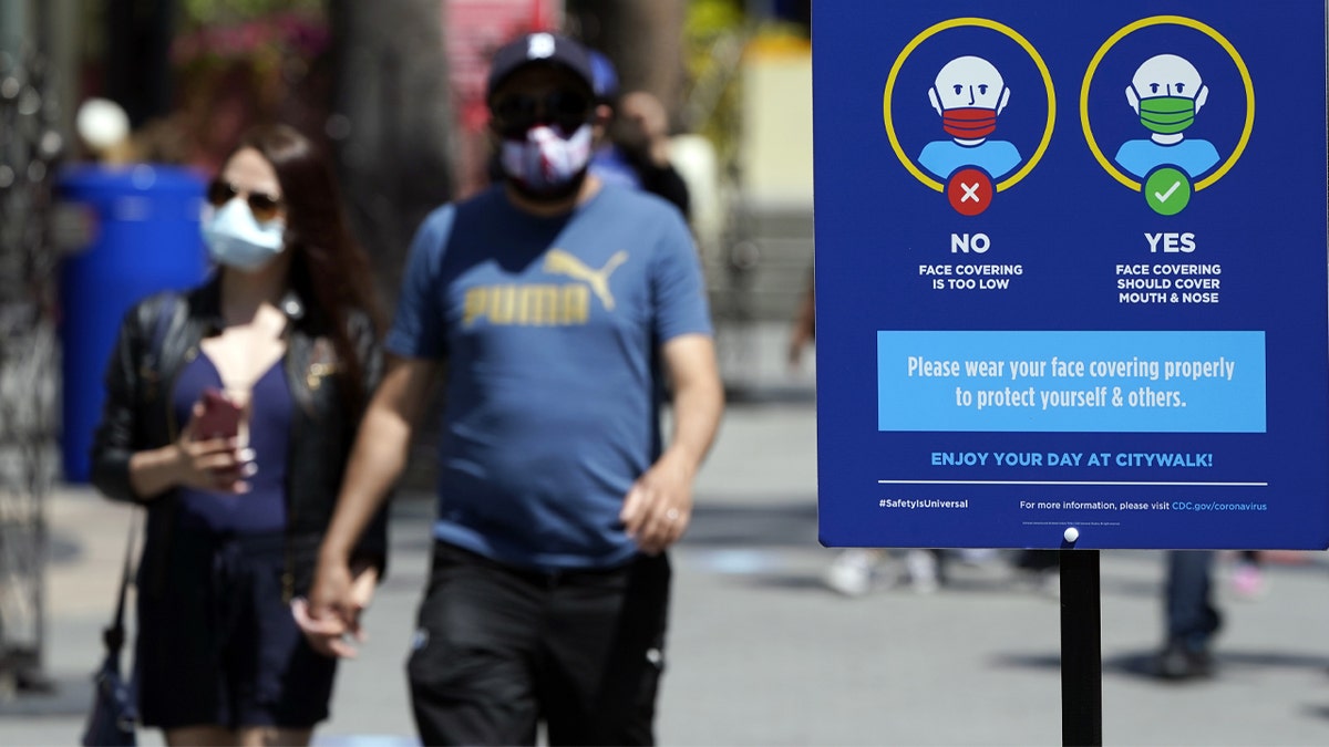 FILE - In this May 14, 2021, file photo, signs instruct visitors on the proper way to wear masks at the Universal City Walk in Universal City, Calif. California is keeping its rules for wearing facemasks in place until the state more broadly lifts its pandemic restrictions on June 15. State officials said Monday, May 17 that the delay will give people time to prepare, and for the state to make sure that virus cases stay low. (AP Photo/Marcio Jose Sanchez, File) 