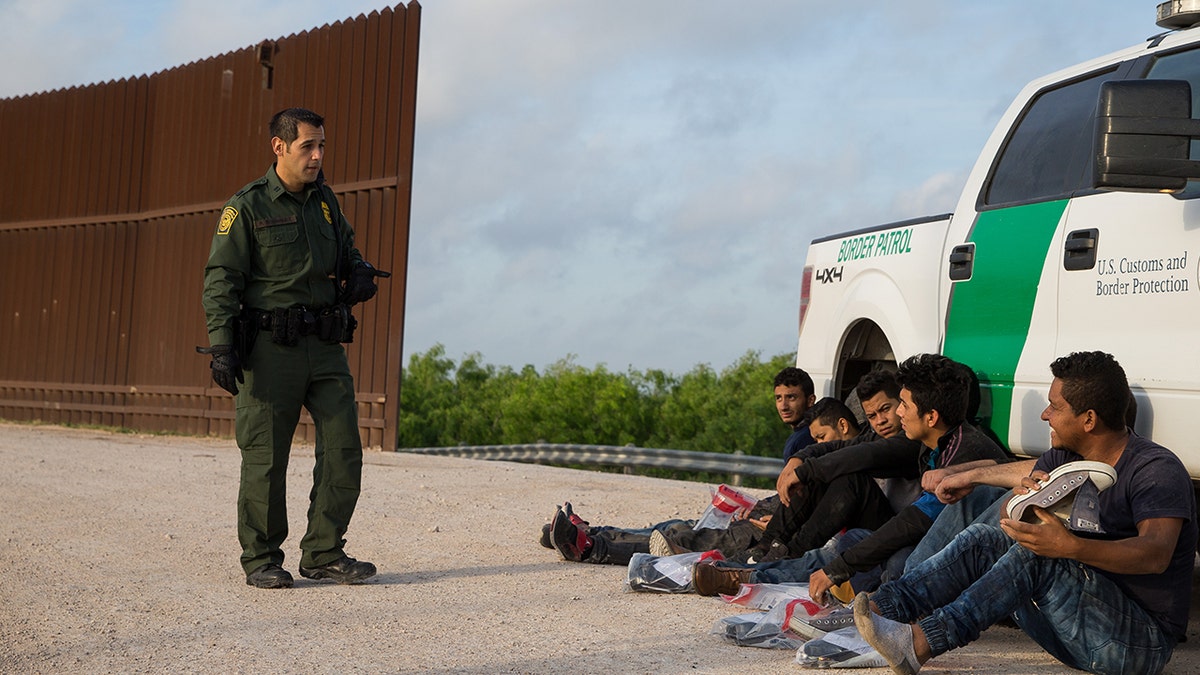 A Border Patrol agent apprehends illegal immigrants shortly after they crossed the border from Mexico into the United States on Monday, March 26, 2018 in the Rio Grande Valley Sector near McAllen, Texas. 