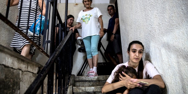 People in Ashdod, Israel take shelter in the stairwell of their apartment building during a siren warning of rockets fired from Gaza to Israel on May 18, 2021.(Associated Press)