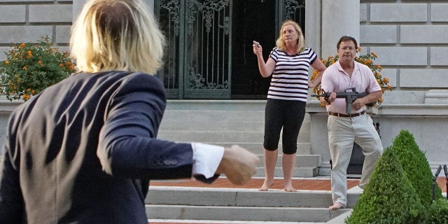 Patricia and Mark McCloskey draw their firearms on protestors as they enter their neighborhood during a protest against St. Louis Mayor Lyda Krewson, in St. Louis, Missouri, U.S. June 28, 2020. Picture taken June 28, 2020.  REUTERS/Lawrence Bryant