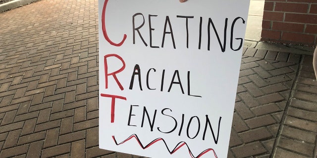 A protester holds a sign outside a building as the Noblesville school board meets inside on Tuesday, May 4, 2021.
