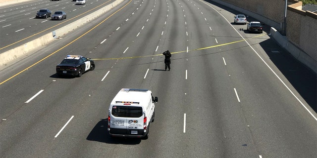 A crime scene investigator photographs the scene while the California Highway Patrol secures the northbound lanes of the 55 Freeway near Chapman Avenue were a 6-year-old boy was fatally shot during apparent road rage incident Friday, 可能 21, 2021 in Orange, 那.
