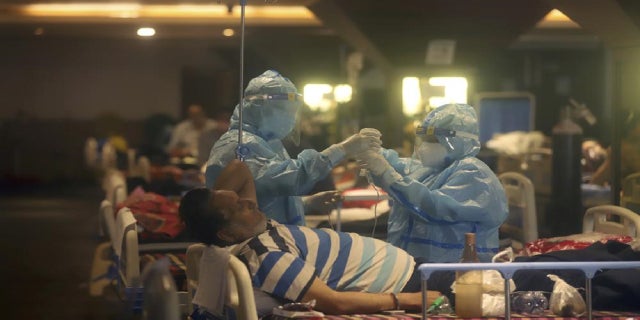 In this April 30, 2021 file photo, healthcare workers tend to COVID-19 patients at a makeshift hospital in New Delhi, India.