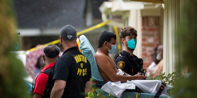 Paramedics transport a man into an ambulance from the scene of a human smuggling case, where more than 90 undocumented immigrants were found inside a home on the 12200 block of Chessington Drive, Friday, April 30, 2021, in Houston. 