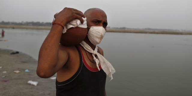 Family member of a COVID-19 victim carries the urn containing the ashes for immersion to perform last rites at Sangam, the confluence of rivers Ganges and Yamuna in Prayagraj, India, Saturday, May 1, 2021. India on Saturday set yet another daily global record with 401,993 new cases, taking its tally to more than 19.1 million. Another 3,523 people died in the past 24 hours, raising the overall fatalities to 211,853, according to the Health Ministry. Experts believe both figures are an undercount. (AP Photo/Rajesh Kumar Singh)