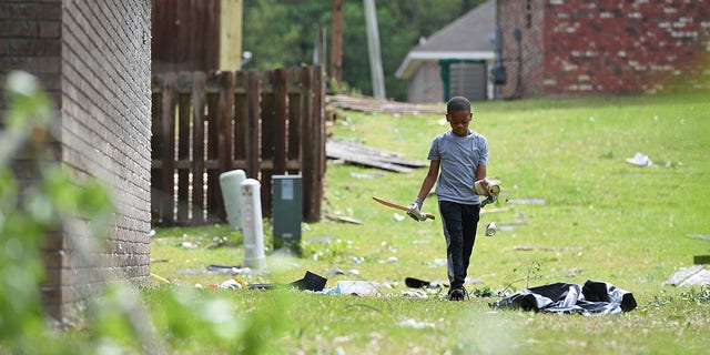 Derrick Pounds Jr., 7, picks up debris around his house on Elvis Presley Drive in Tupelo, Miss., Monday, May 3, 2021. Multiple tornadoes were reported across the state on Sunday. (AP Photo/Thomas Graning)