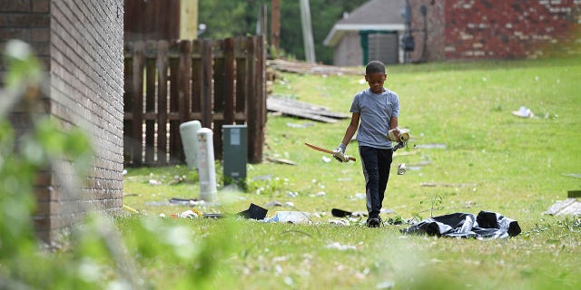 Derrick Pounds Jr., 7, picks up debris around his house on Elvis Presley Drive in Tupelo, Miss., Monday, May 3, 2021. Multiple tornadoes were reported across the state on Sunday. (AP Photo/Thomas Graning)
