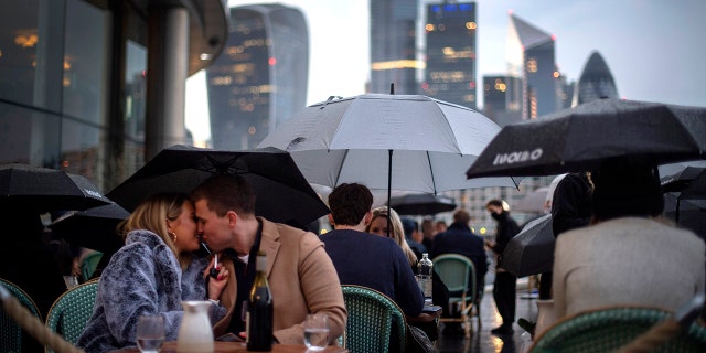 People endure the wet and windy Bank Holiday weekend weather to sit outside a restaurant near Tower Bridge in central London on Monday, May 3, 2021.