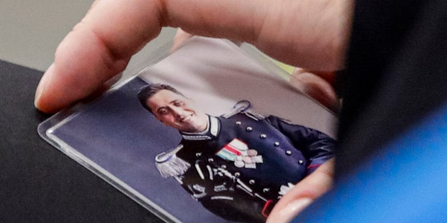 In this Wednesday, Sept. 9, 2020 file photo, Rosa Maria Esilio, widow of Italian Carabinieri paramilitary police officer Mario Cerciello Rega, holds a photograph of her husband ahead of a hearing of the trial in which two American tourists are accused of his murder in Rome. (AP Photo/Alessandra Tarantino, Pool)