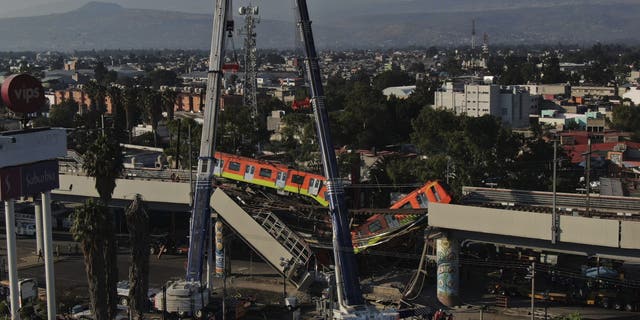 Subway cars dangle at an angle from a collapsed elevated section of the metro, in Mexico City, Tuesday, May 4, 2021. (AP Photo/Fernando Llano)