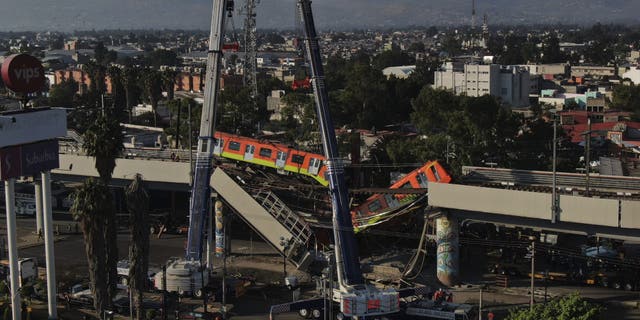 Subway cars dangle at an angle from a collapsed elevated section of the metro, in Mexico City, Tuesday, May 4, 2021. (AP Photo/Fernando Llano)