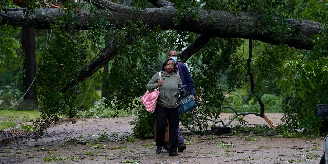 Northeast Jackson, Miss., residents leave their powerless home after utility lines were brought down by trees and debris spread by high winds Tuesday, May 4, 2021. The severe weather was not unexpected, since the state was hit with a number of tornadoes on Sunday. (AP Photo/Rogelio V. Solis)