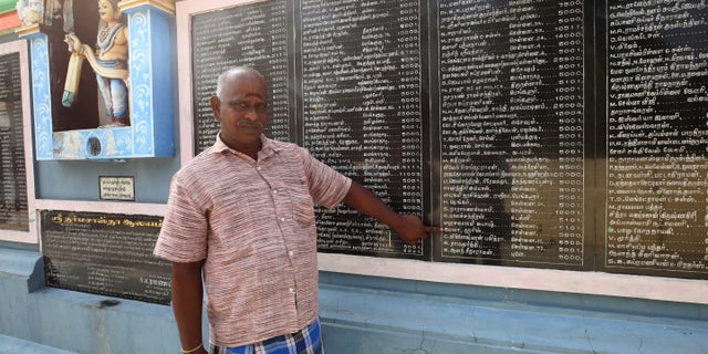 FILE - In this Nov. 3, 2020, file photo, a villager points out the name of Kamala Harris written in Tamil language and the amount she donated for the renovation of temple through her relative, in Thulasendrapuram village, south of Chennai, Tamil Nadu state, India. The lush green village is the hometown of Harris' maternal grandfather who migrated from there decades ago. (AP Photo/Aijaz Rahi, File)