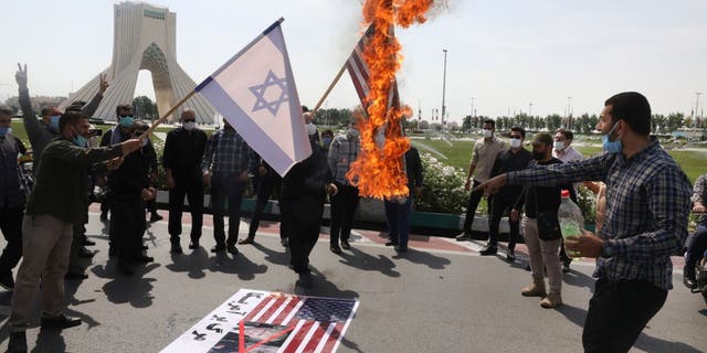 Demonstrators burn representations of Israeli and U.S flags during the annual Al-Quds, or Jerusalem, Day rally, with the Azadi (Freedom) monument tower seen at left, in Tehran, Iran, Friday, May 7, 2021. 