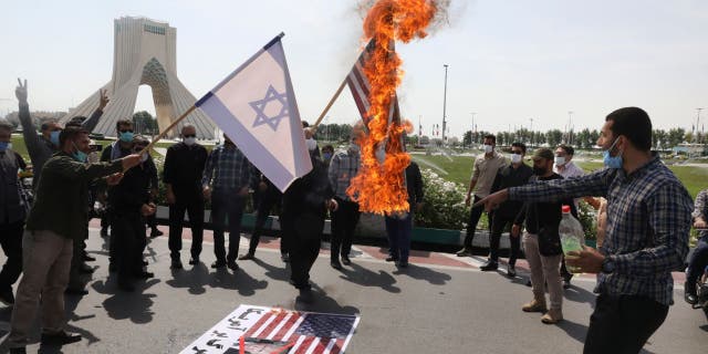 Demonstrators burn representations of Israeli and U.S flags during the annual Al-Quds, or Jerusalem, Day rally, with the Azadi (Freedom) monument tower seen at left, in Tehran, Iran, Friday, May 7, 2021. 