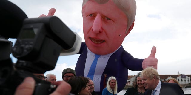 British Prime Minister Boris Johnson speaks to the media next to a large inflatable of him and flanked by Jill Mortimer, the winning Conservative Party candidate of the Hartlepool by-election on May 7, 2021.(AP Photo/Scott Heppell)