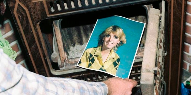 his undated photo provided by the Yavapai County Sheriff's Office shows a law enforcement official discovering a photograph of Pamela Pitts in the wood stove of a home she shared with two others in Prescott, Ariz., in 1988. Pitts' then-roommate, Shelly Harmon, recently confessed to killing Pitts and was sentenced to time she already had served in another killing. (Yavapai County Sheriff's Office via AP)